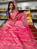 Woman wearing a pink saree with gold patterns in a store setting