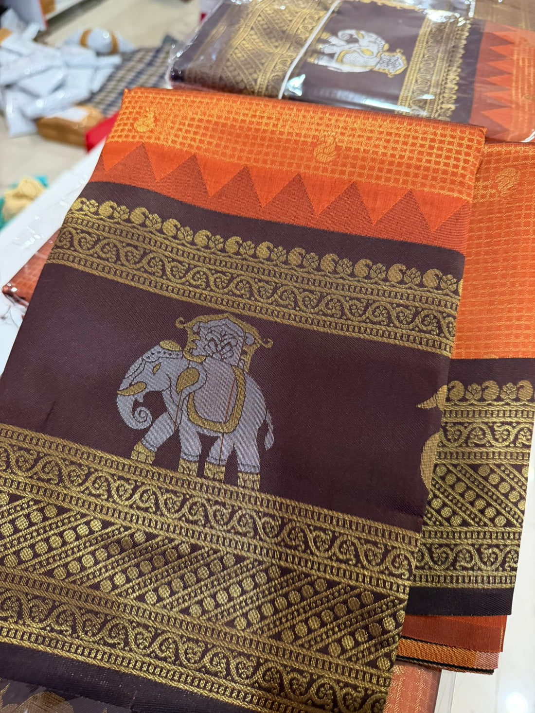 Brown and orange saree with elephant design on a table